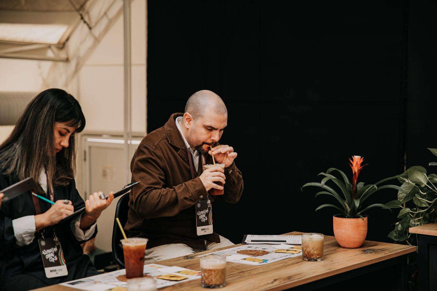 Two evaluators scoring beverage samples at a table